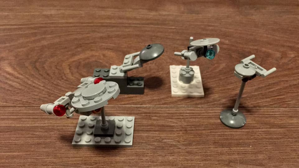 Four custom built Lego Star Trek Enterprises starting with a 4-stud diameter round plate followed by smaller versions using different Lego dishes and a round piece.